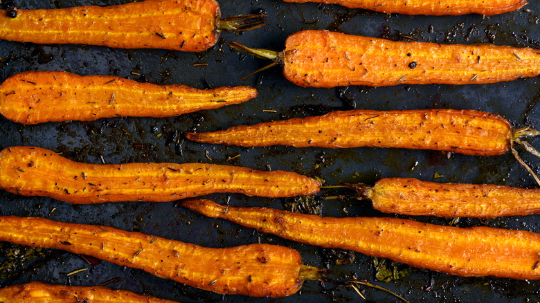 Halved roasted carrots on black background