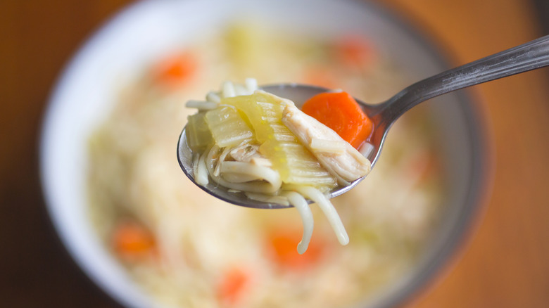 Spoonful of chicken noodle soup over bowl