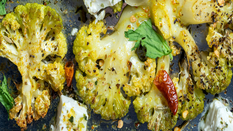 roasted cauliflower and feta on a baking sheet with herbs and spices