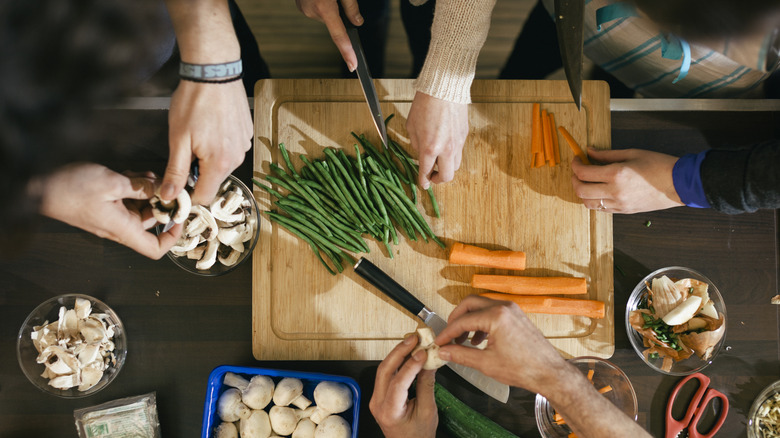 overhead view of various hands prepping asparagus, carrots, and mushrooms