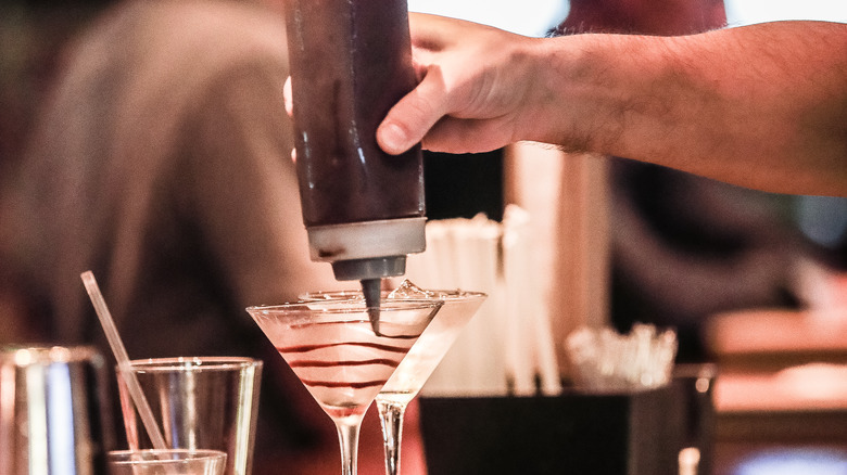 bartender drizzles chocolate sauce into glass