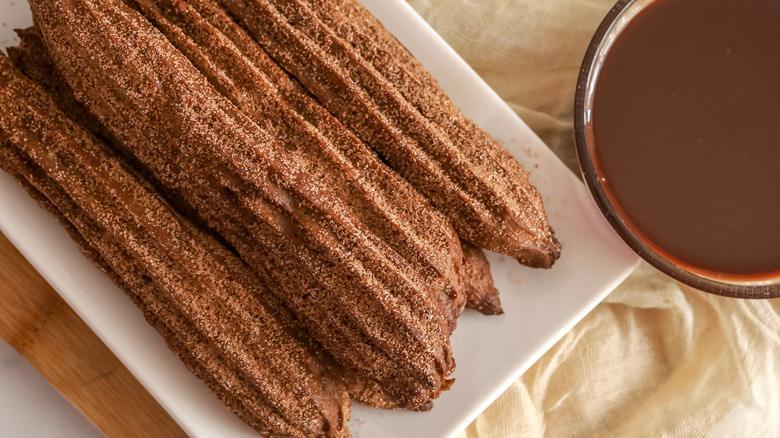 Churros on plate next to chocolate dipping sauce