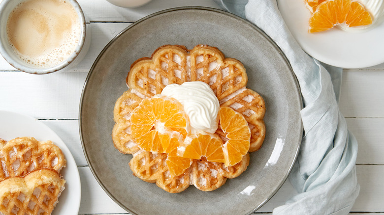 waffle topped with orange slices and whipped cream