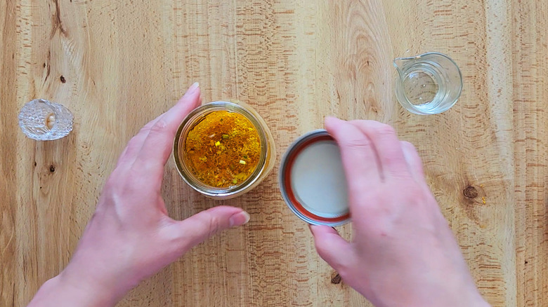 hands closing jar of vinaigrette
