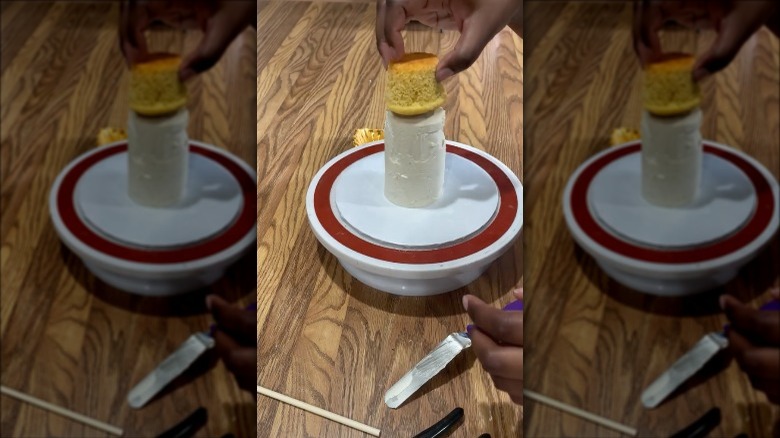 a person building a mini layer cake out of cupcakes