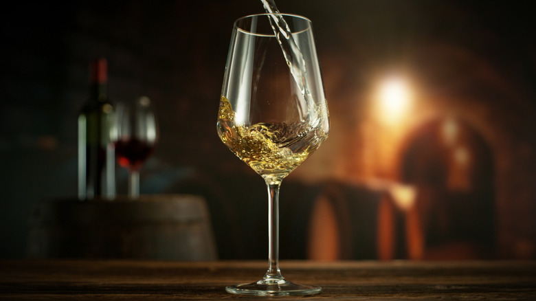 White wine being poured into a glass at a dark-lit dive bar