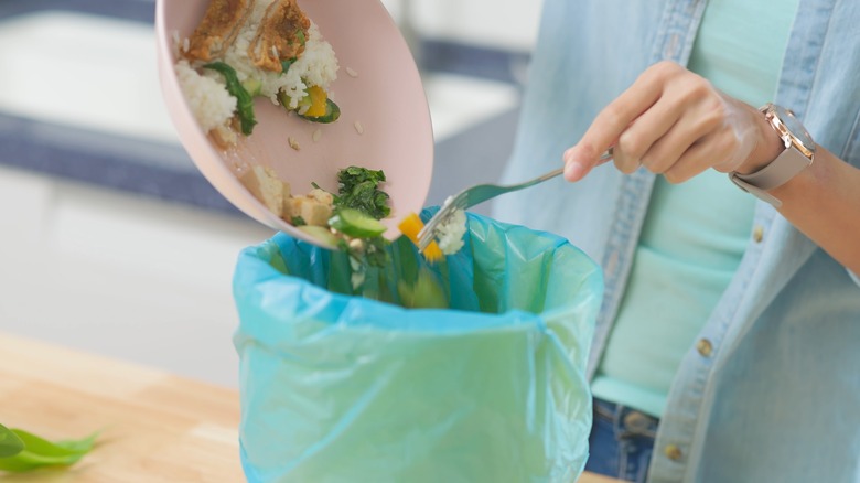 Person scraping a plate clean into the trash