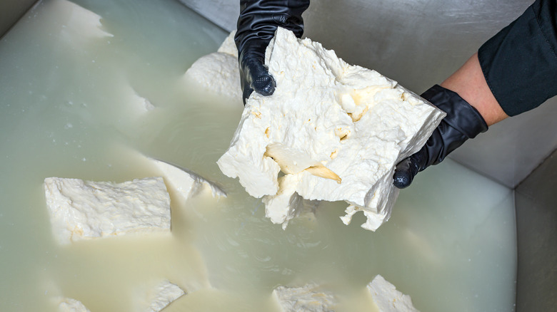 hands placing feta in brine