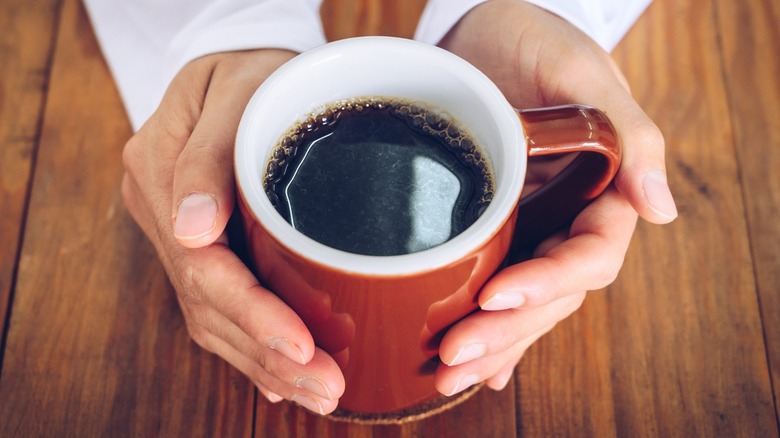 Hands cupping a mug of coffee