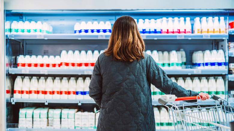 A woman standing in front of milk cartons.