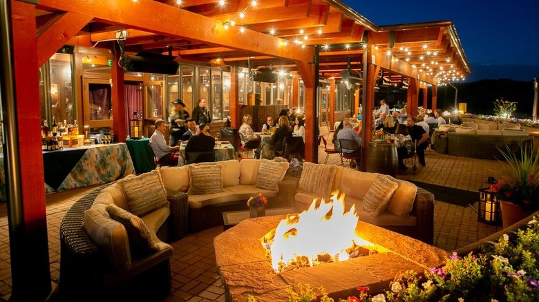 Couches around an outdoor firepit at The Fort with diners eating at tables in the background