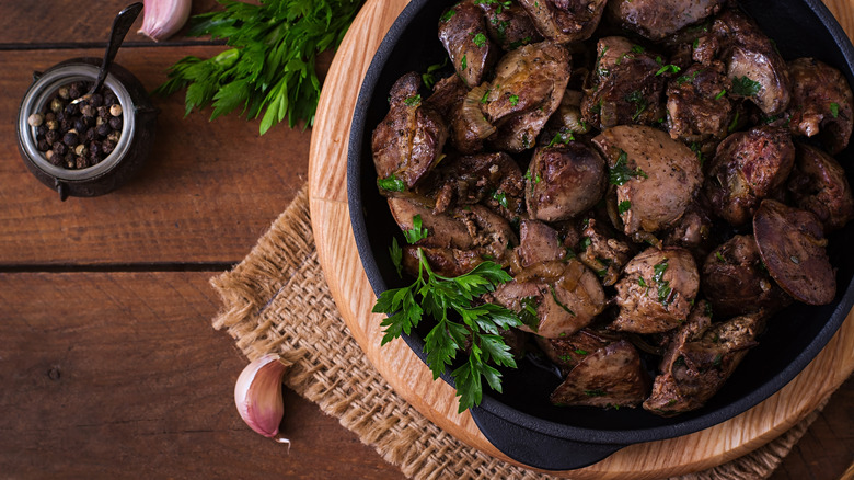 Fried chicken livers in a pan with parsley, garlic, and peppercorns