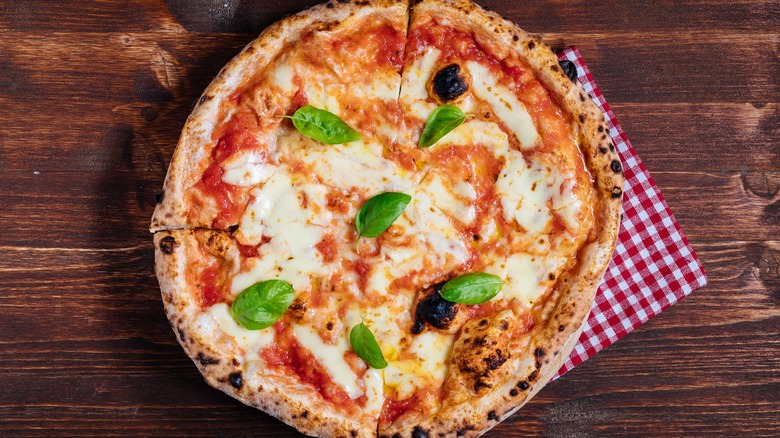 Pizza with cheese, sauce, and basil on wooden table