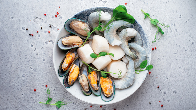 Raw scallops, shrimp, and mussels in a bowl