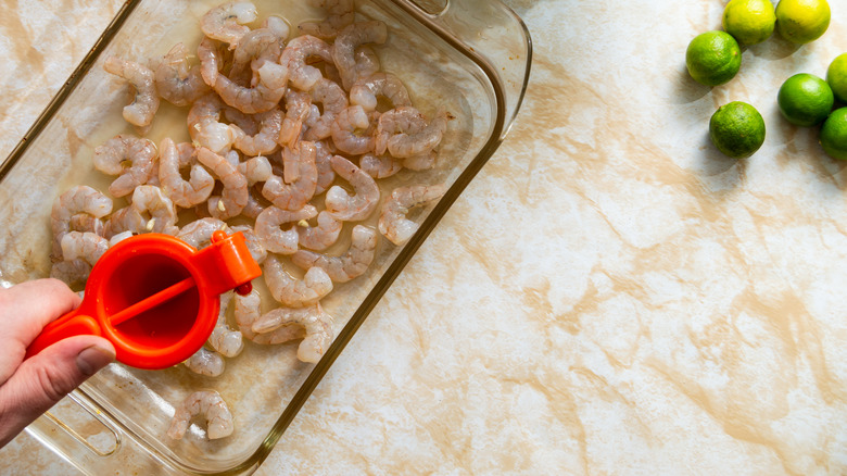 squeezing lime juice over raw shrimp