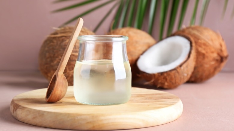 Jar of coconut oil with coconut in the background