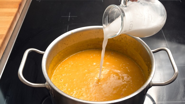 Cream being poured into pumpkin soup