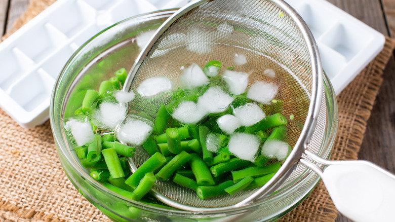 removing green beans from ice water with mesh strainer