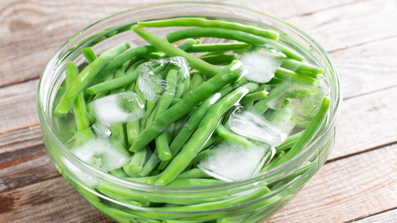 green beans sitting in a bowl filled with ice water