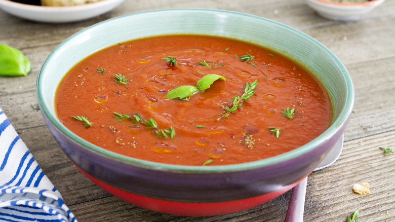 Bowl of tomato soup garnished with herbs 
