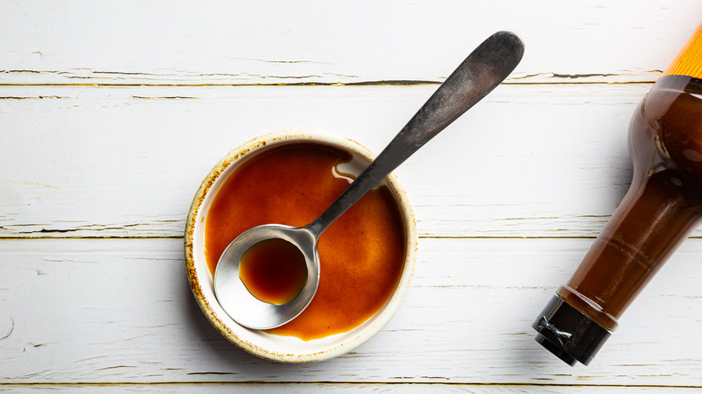 worcestershire sauce in a bowl with a spoon, tip of bottle visible