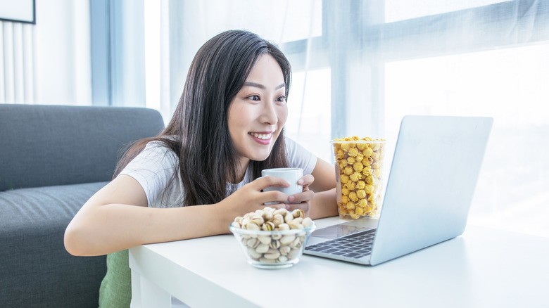 woman watching laptop with snacks