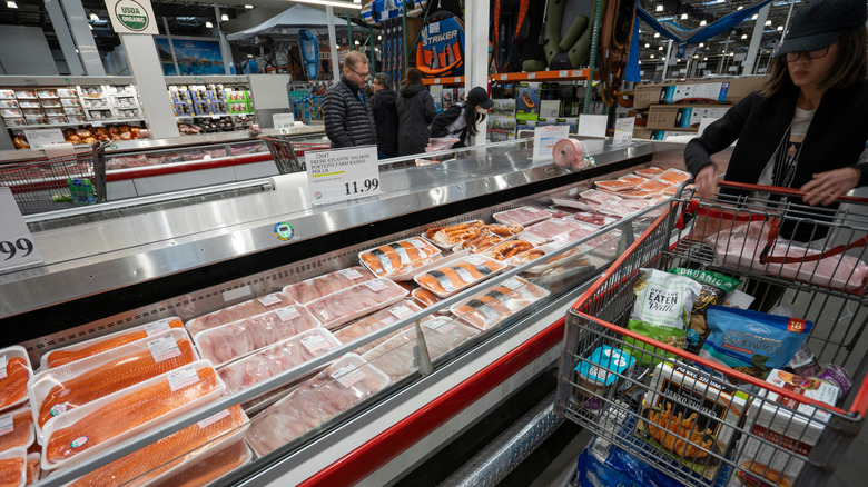 Costco shopper browsing aisle with salmon and shopping cart