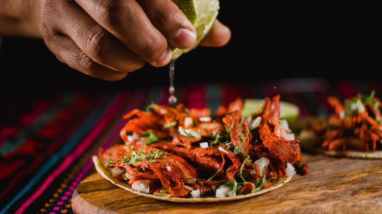 squeezing lime juice on a plate of pork al pastor