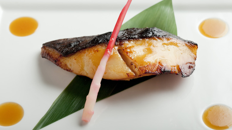 Miso-marinated black cod with the skin on resting on top of a geometrically cut banana leaf
