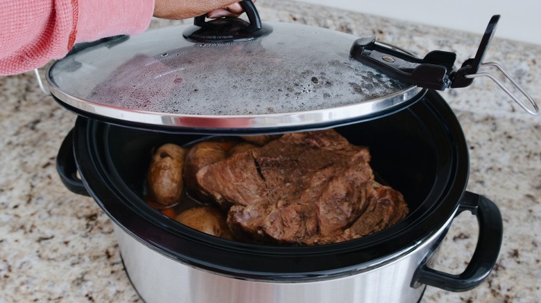 Hand picking up Crockpot lid