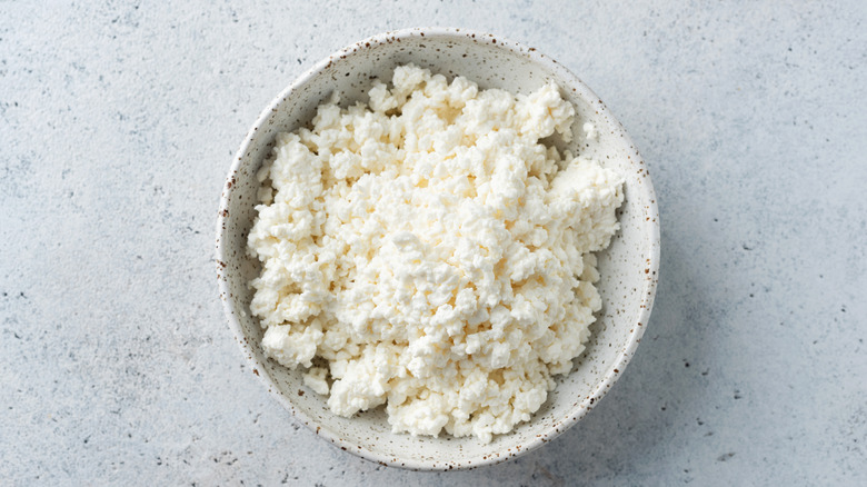 Bowl of cottage cheese on white background