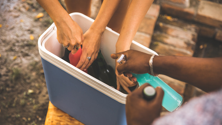 People reaching in a cooler