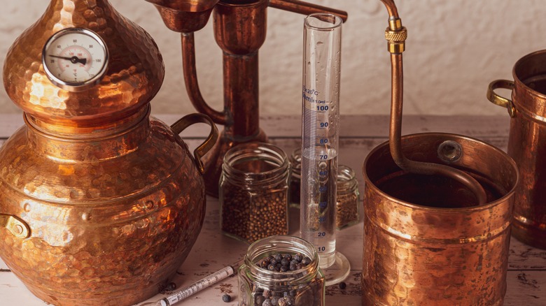 pot still and jars of juniper, cardamom, and clove