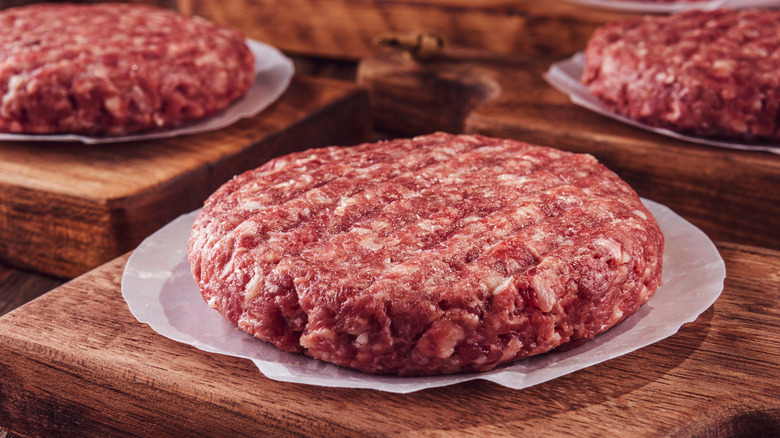 Raw hamburgers on wood pans