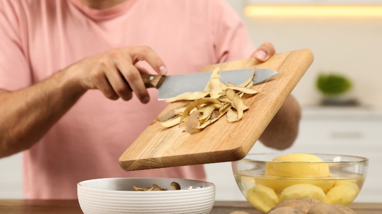 scraping potato peels from cutting board