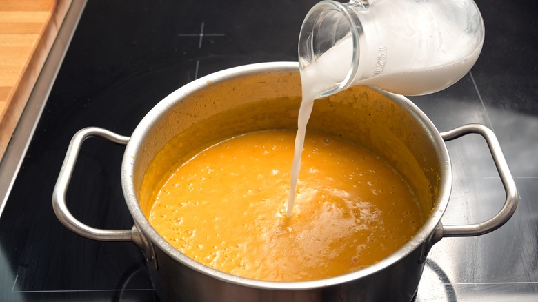 pouring coconut milk into soup