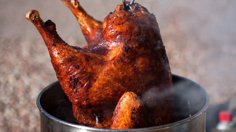 A deep-fried turkey being pulled from a fryer