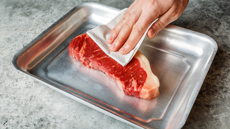 Patting steak down with paper towel