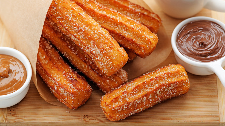 Churros with bowl of chocolate sauce and caramel