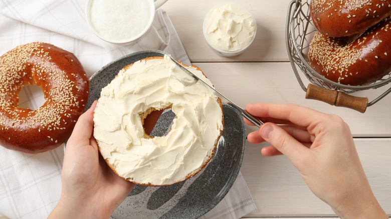 Spreading cream cheese on bagel