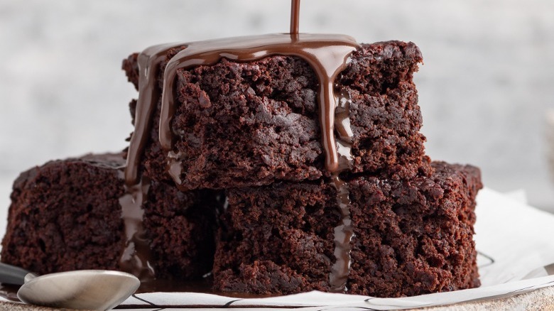 pouring chocolate sauce over brownies