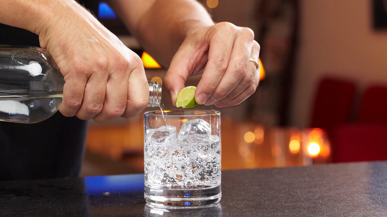 bartender pouring gin into glass