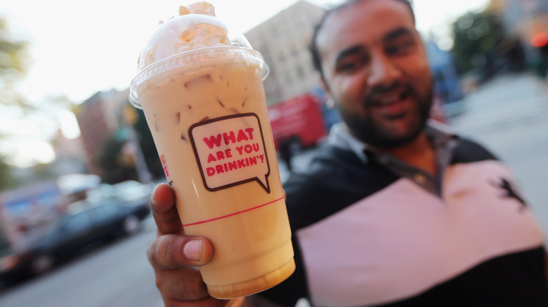 Customer holding a Dunkin iced latte