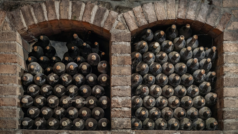 dusty old bottles of wine stacked in two brick alcoves