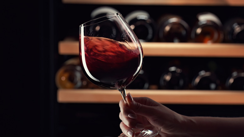 a person swirling a glass of red wine