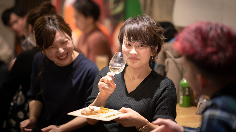 a japanese woman drinking wine and laughing with friends