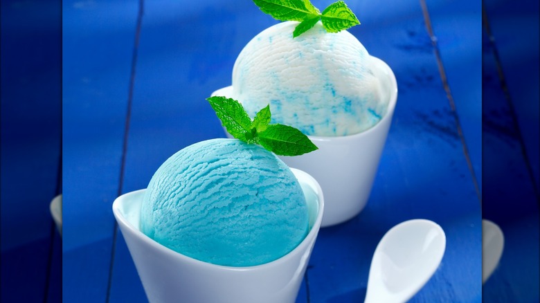 Two containers of blue and blue and white Italian ice garnished with mint