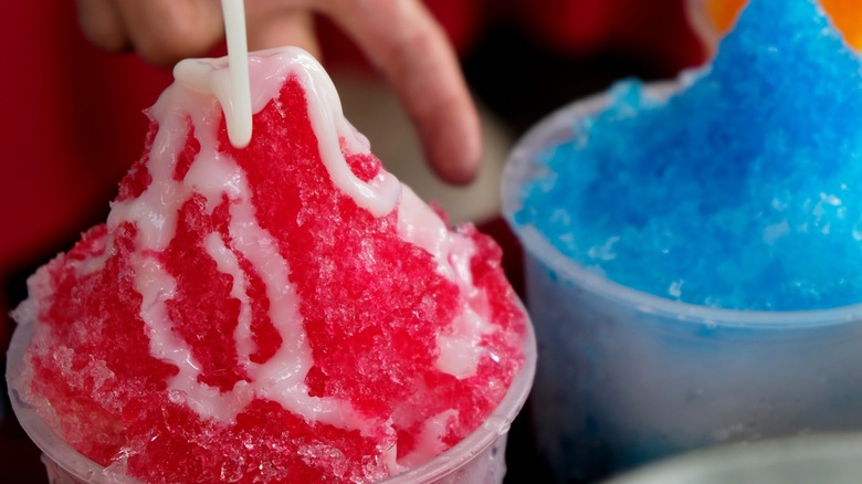 Close-up of condensed milk being drizzled on a cup of red shaved ice