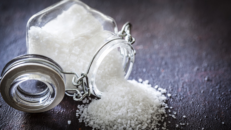 Salt spilling out of glass jar 