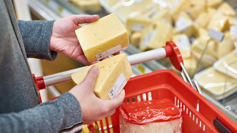 Shopper holding cheeses in grocery store